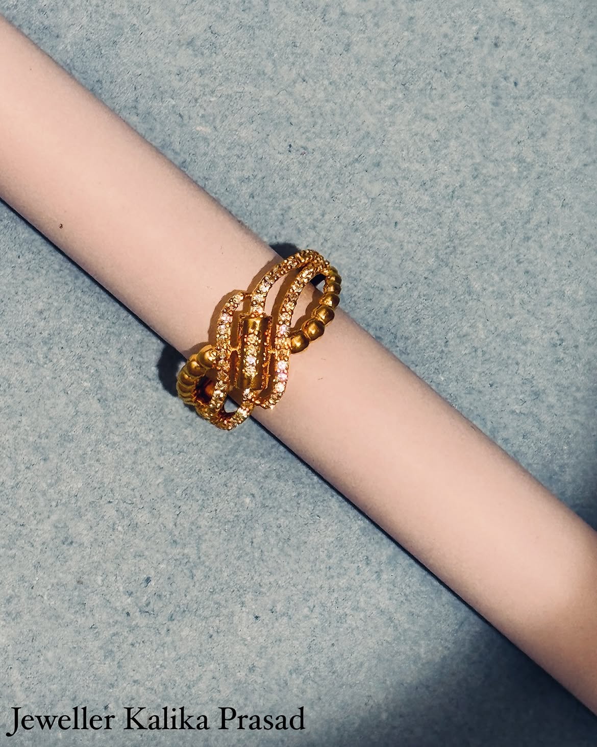 Stacked gold bracelets with intricate bead work