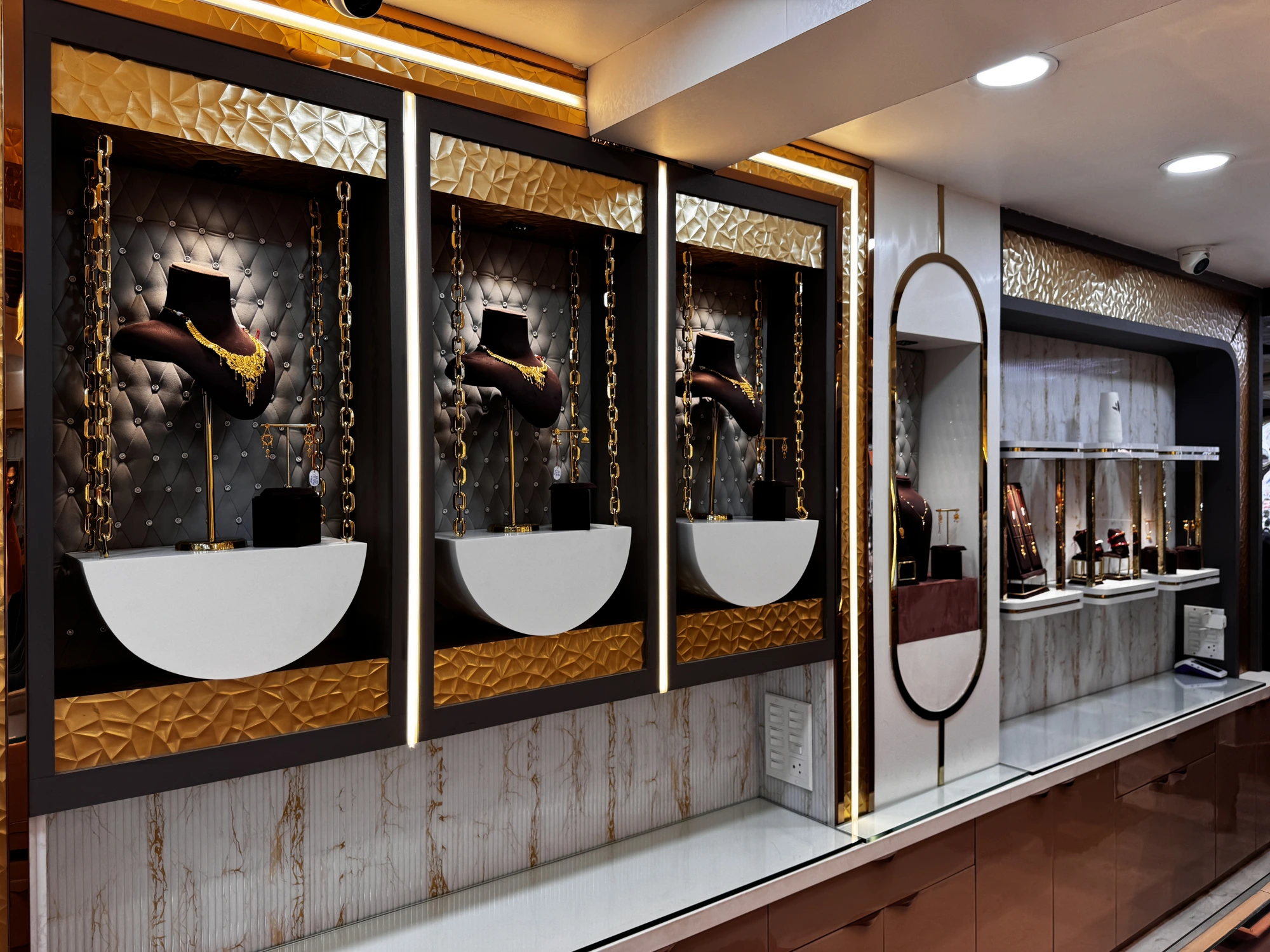 Jeweller Kalika Prasad showroom — crystal chandelier over rows of glass display counters with royal green chairs