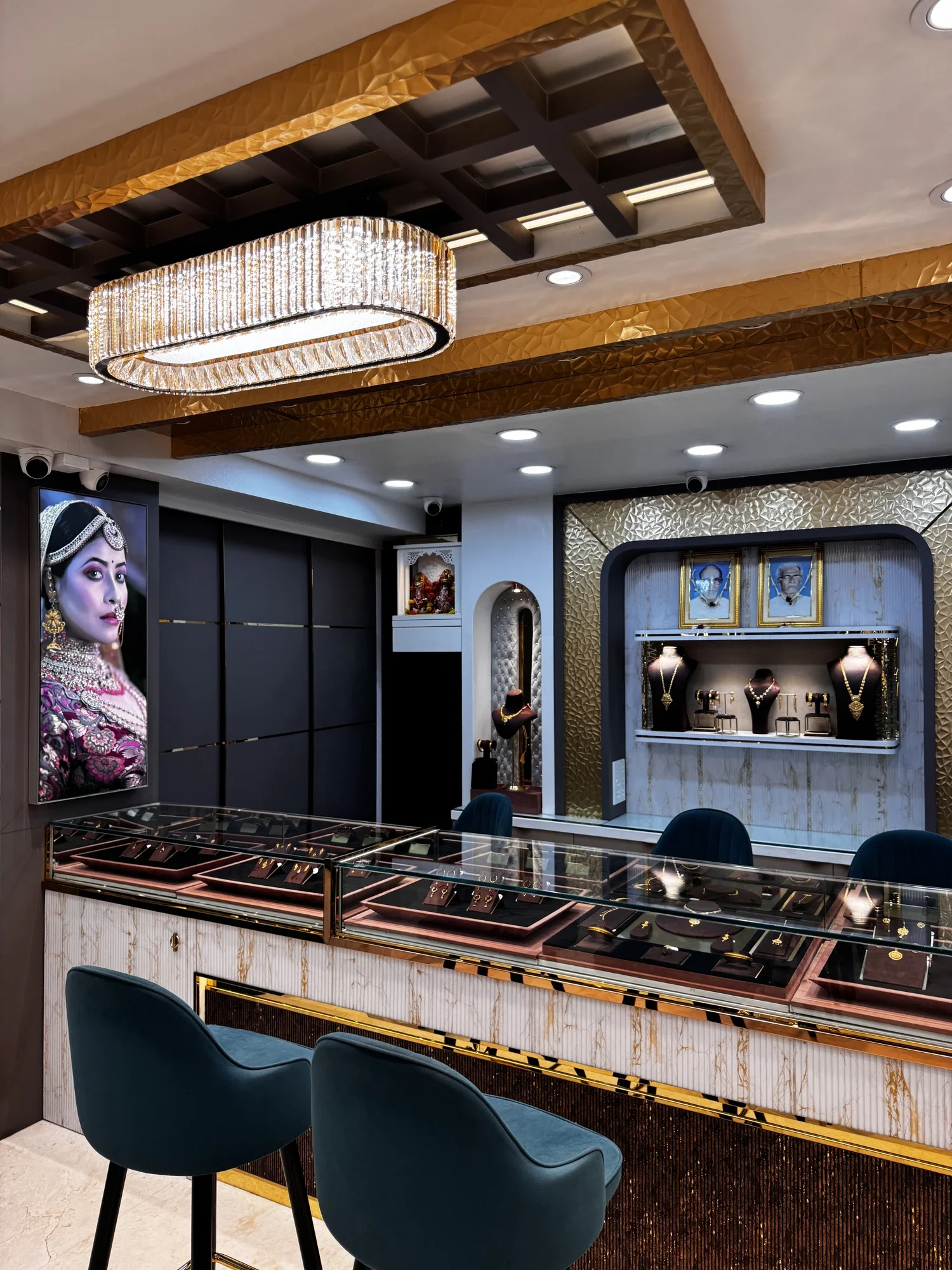 Inside the Jeweller Kalika Prasad showroom — crystal chandelier, glass counters and the founders' portraits on the heritage wall